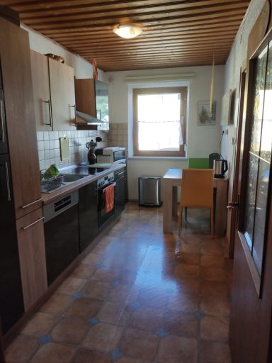 Voll ausgestattete Küche Helle Küche mit Holzdecken, moderner Ausstattung und Tisch neben einem Fenster.